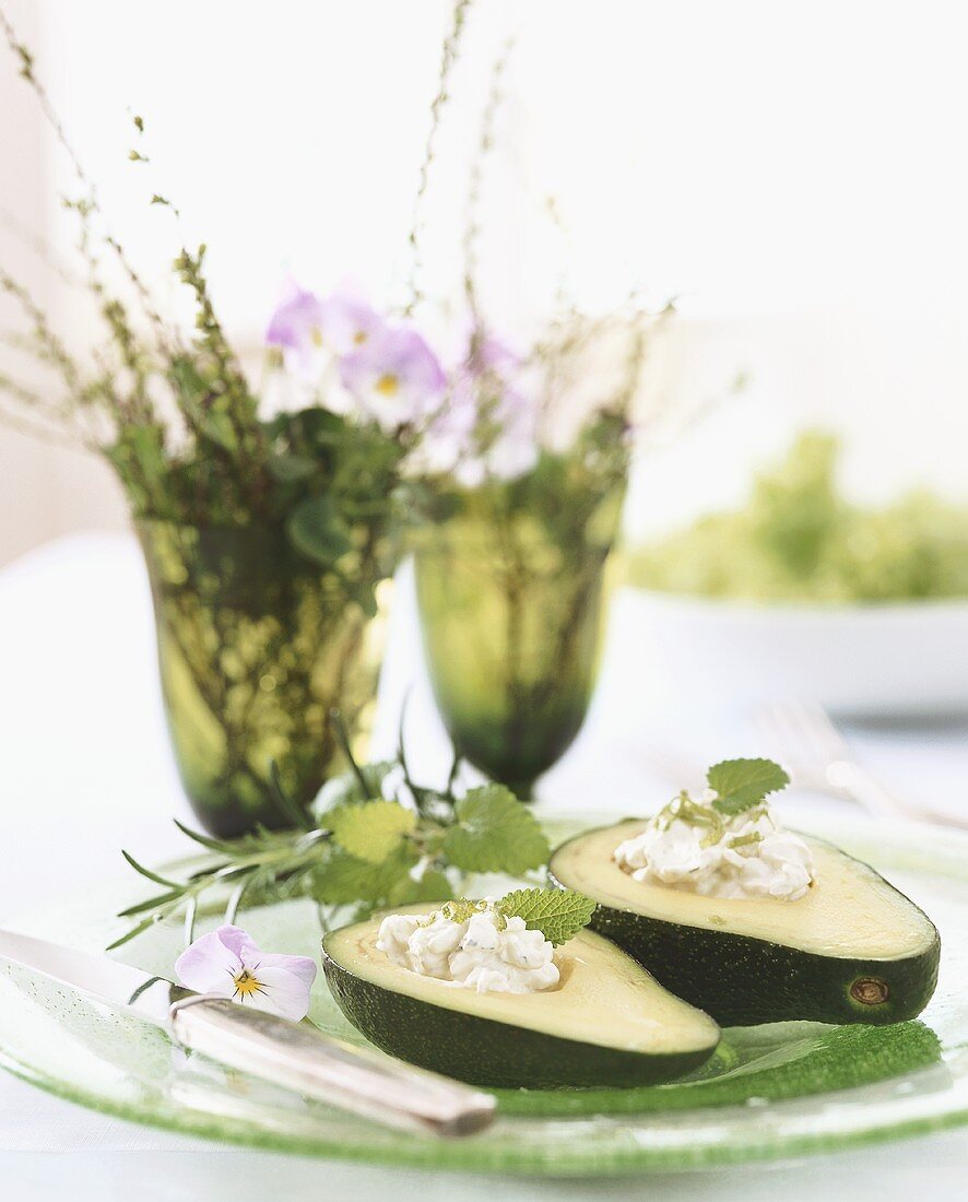 Stuffed avocado with vases of flowers in background