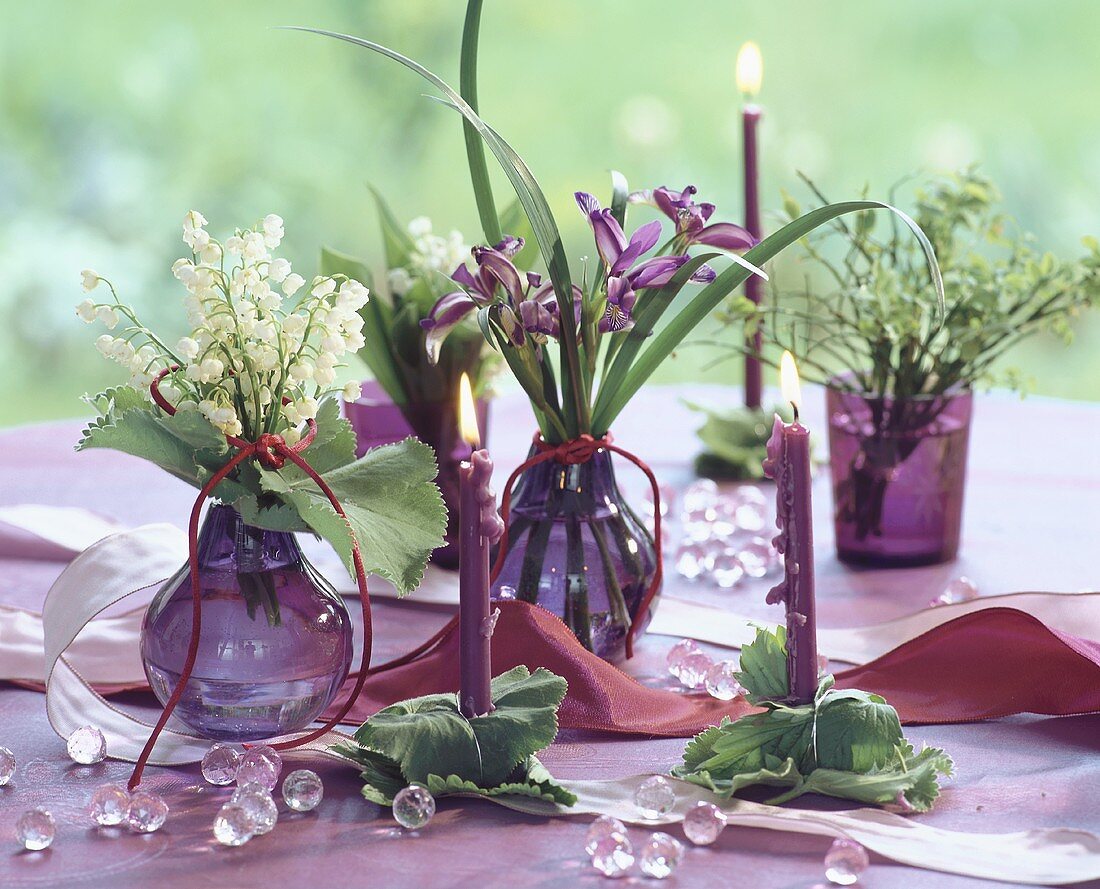 Posies of lilies-of-the-valley & irises & candles on table