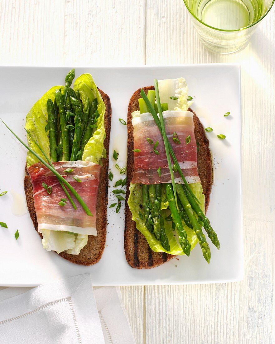 Grilled bread topped with asparagus and bacon salad