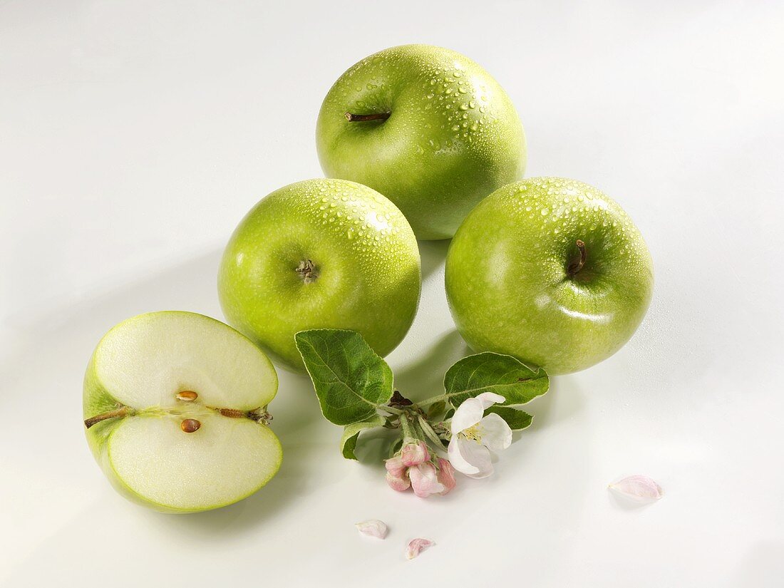 Drei ganze und ein halber Apfel der Sorte Granny Smith