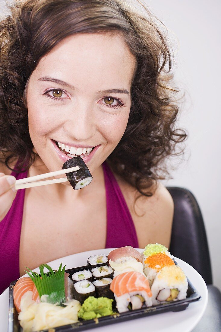 Frau isst Sushi mit Stäbchen