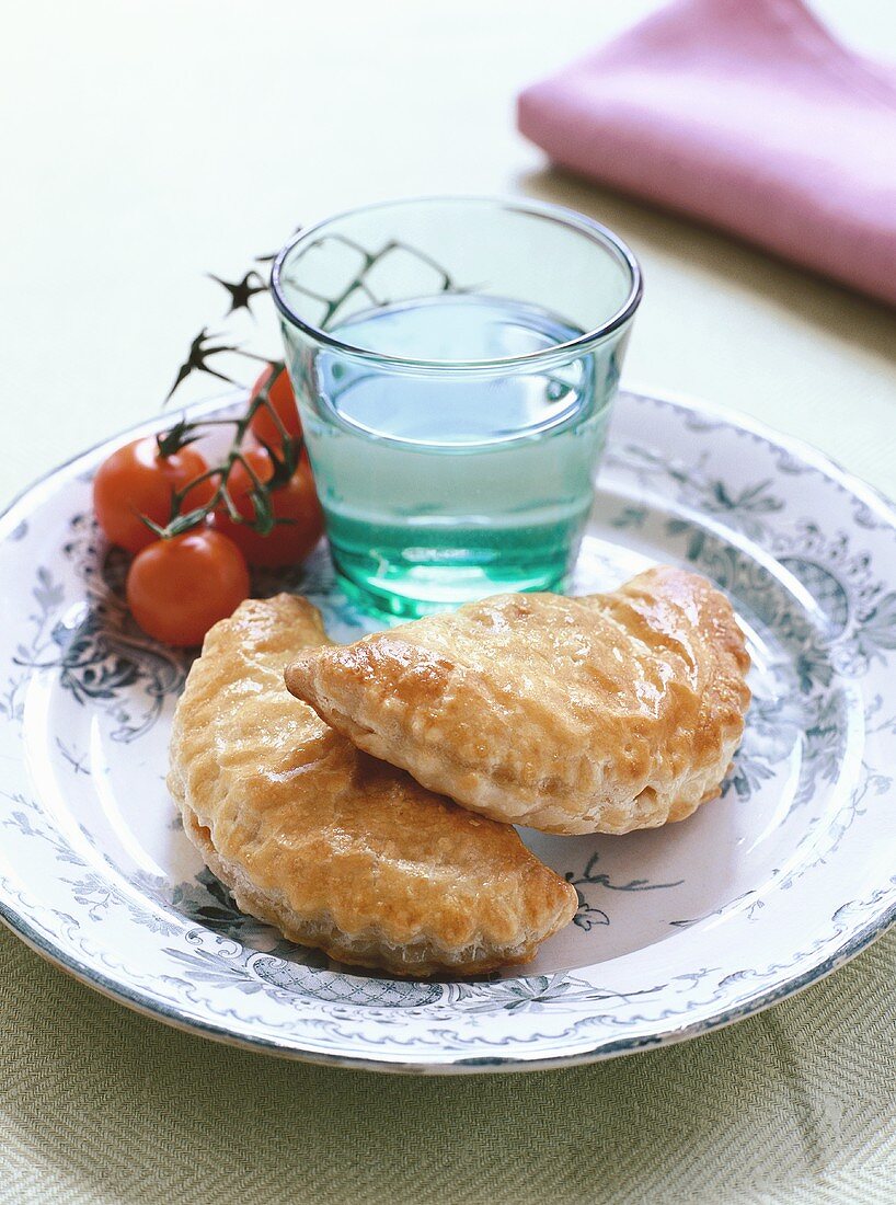 Two pierogi with tomatoes and glass of water