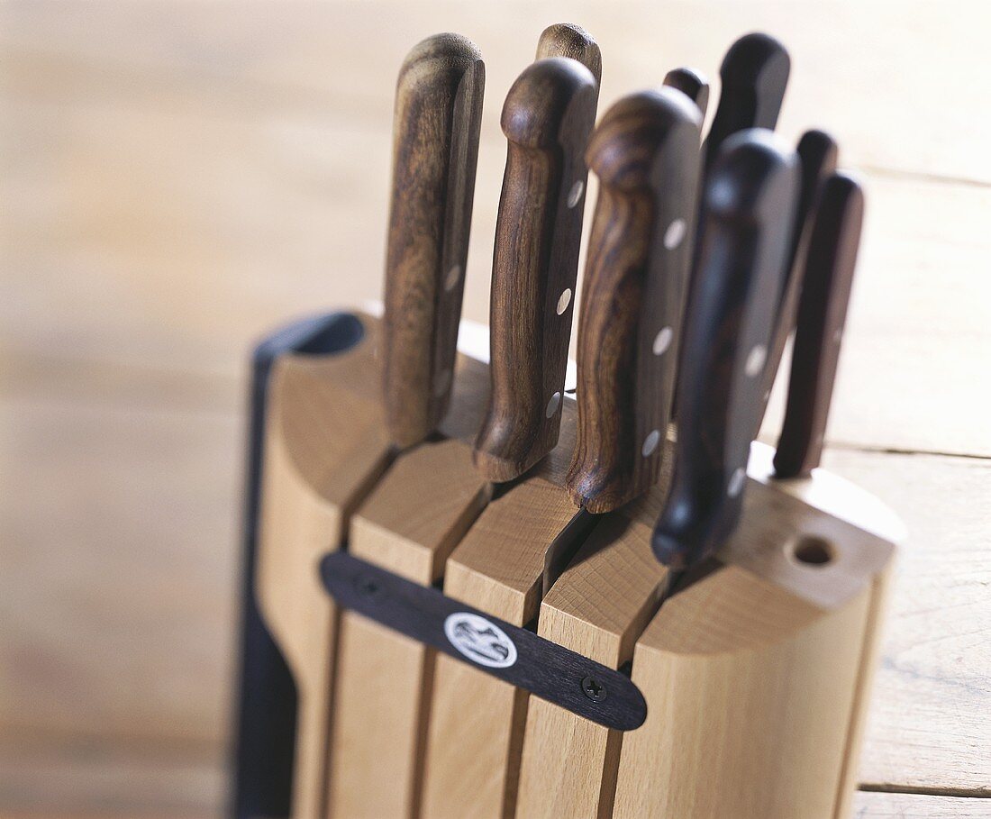 A wooden knife block with various kitchen knives