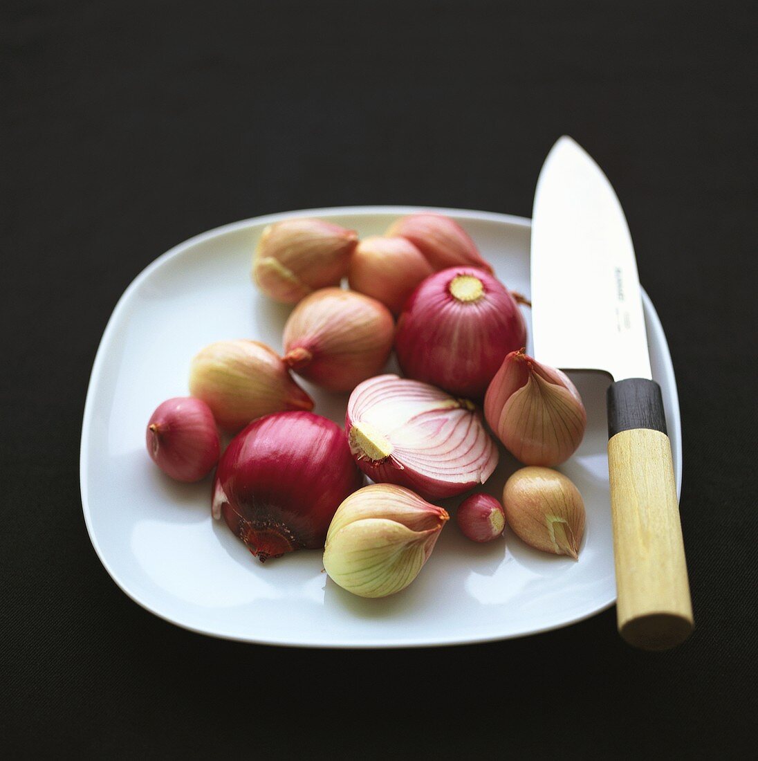 Zwiebeln auf einem Teller mit asiatischem Küchenmesser