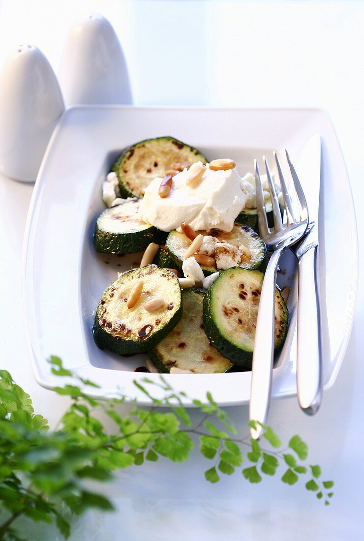 Gebratene Zucchinischeiben mit Schafskäse und Pinienkernen