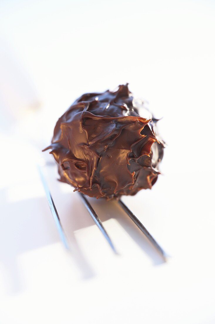 Chocolate truffle with chocolate fork on white background