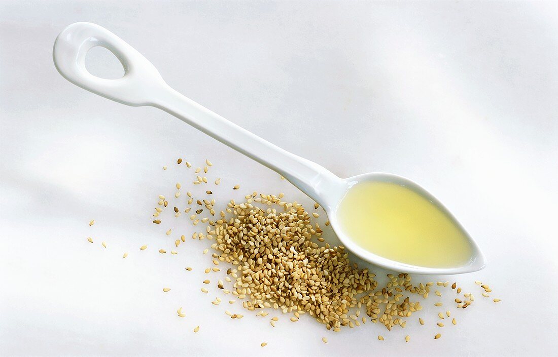 Sesame oil in spoon and sesame seeds
