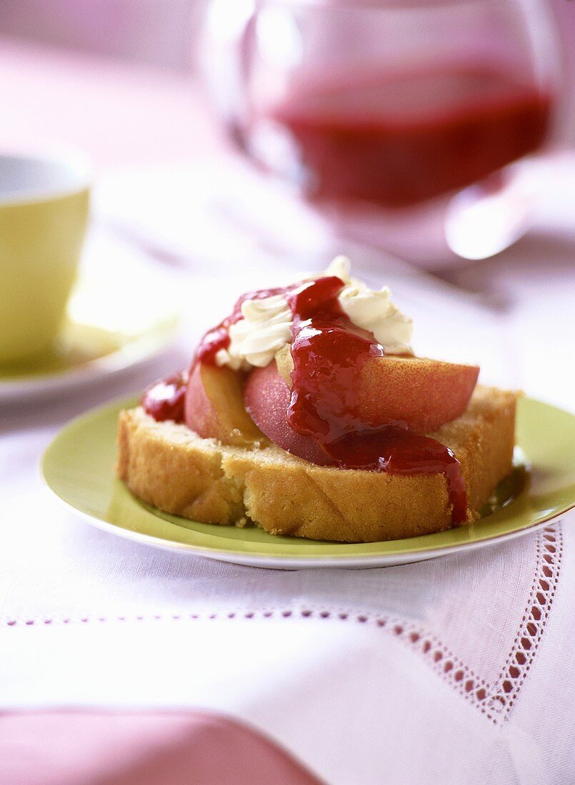 Ein Stück Madeira-Kuchen mit Nektarinen und Erdbeersauce