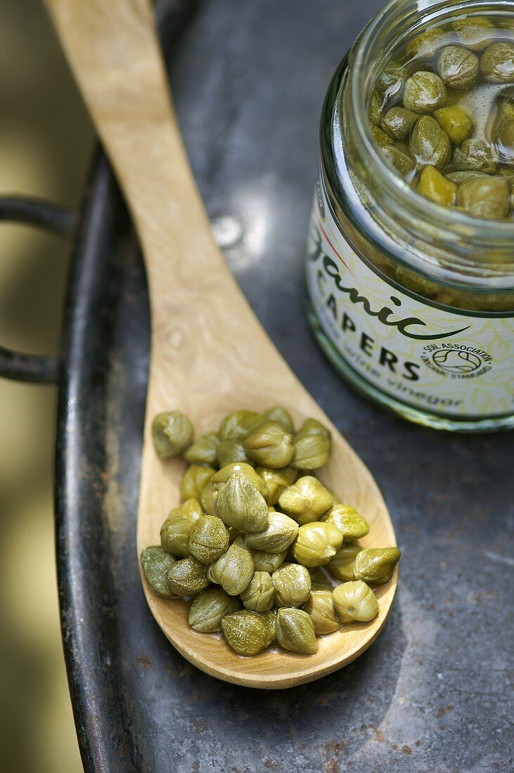 Capers on a wooden spoon and in jar