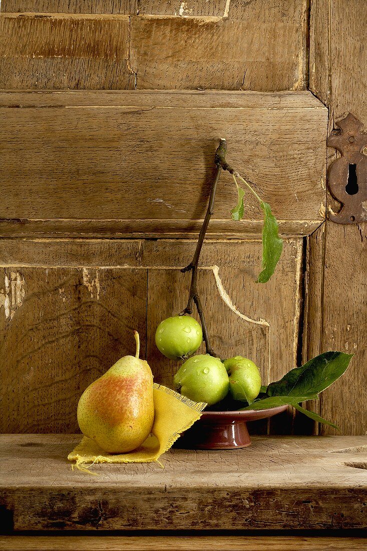 Apples and a pear in front of a wooden door