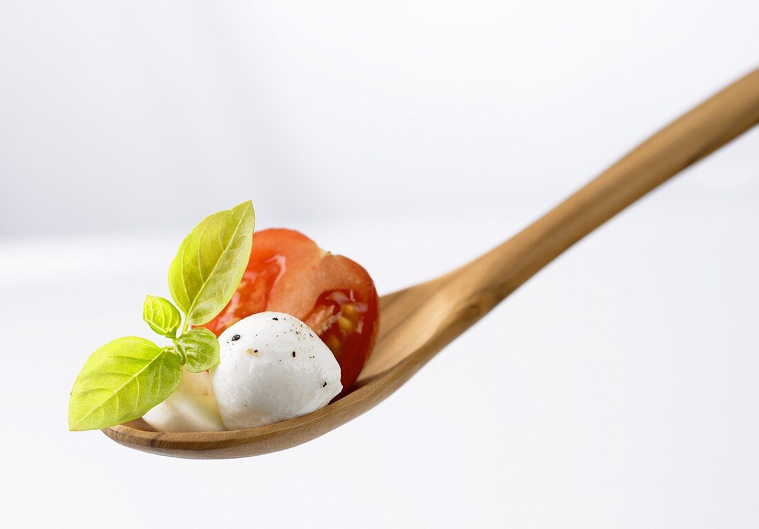 Tomatoes, mozzarella and basil on a wooden spoon