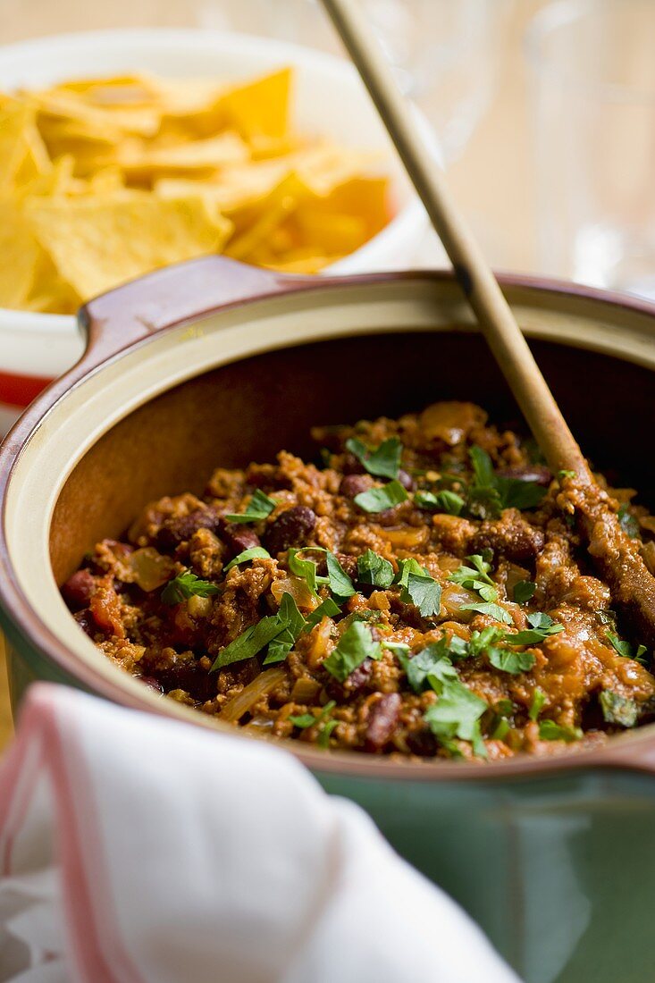 Chili con carne in pan with wooden spoon