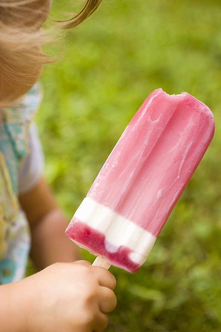 Small girl holding a raspberry ice cream lolly
