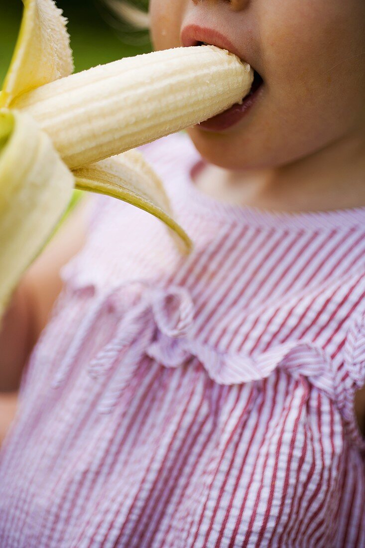 Child taking a bite of banana