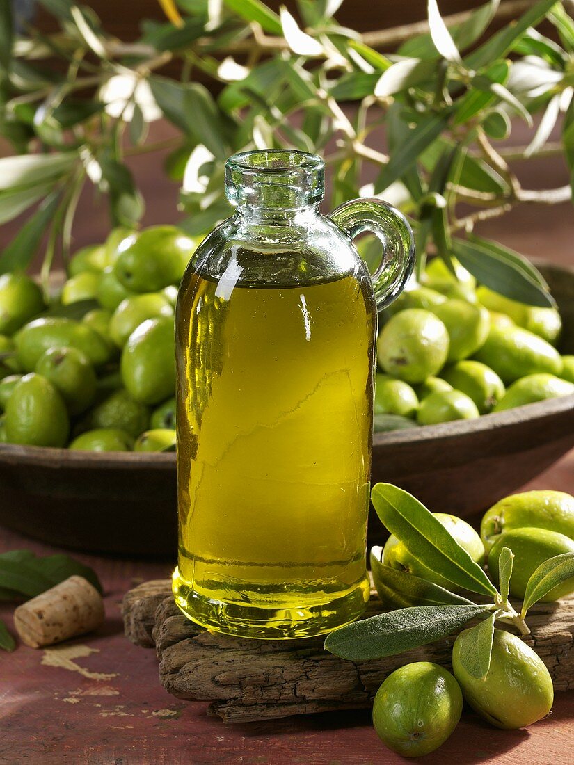 A bottle of olive oil with fresh olives