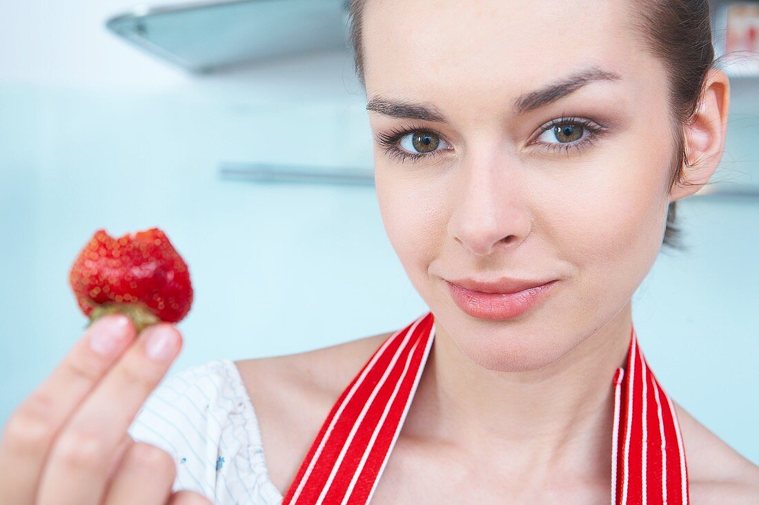Woman holding a strawberry with a bite taken