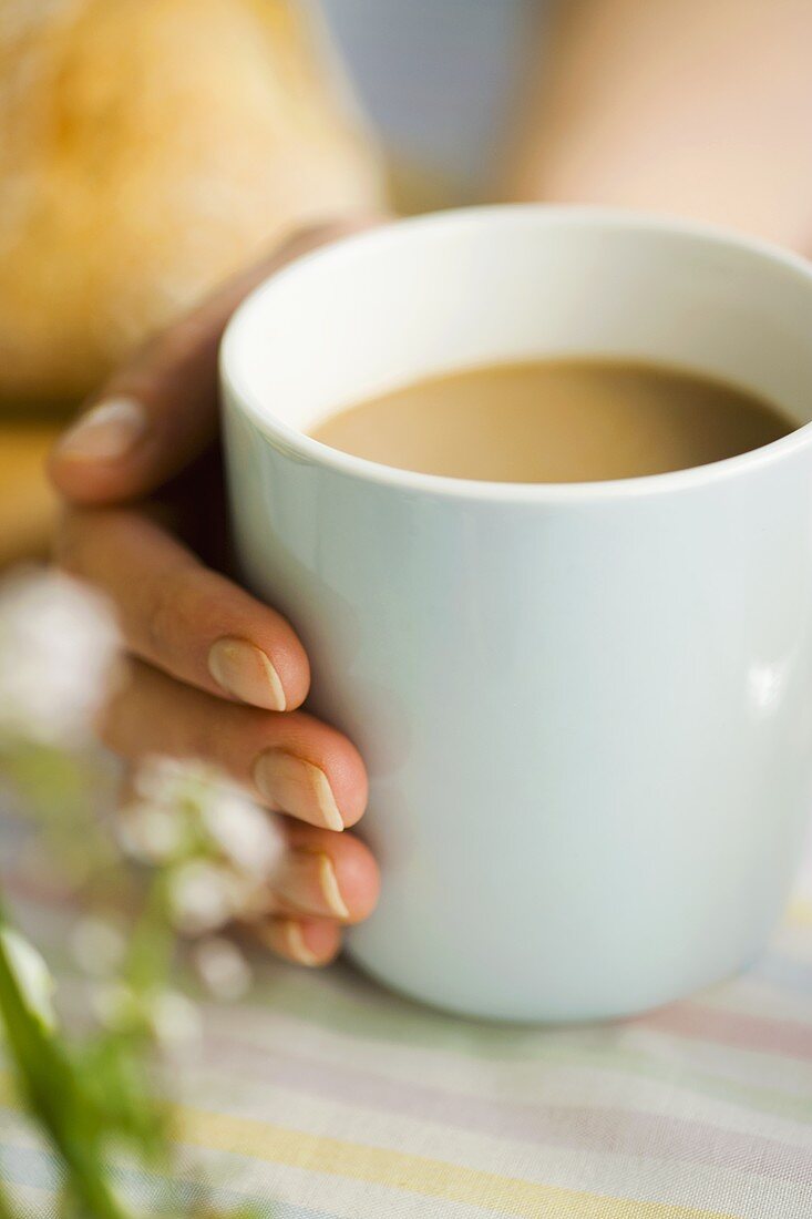 Hand hält eine Tasse Kaffee