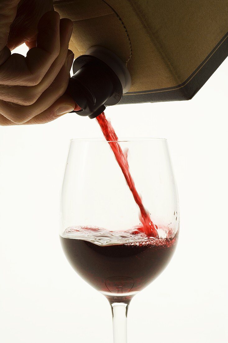 Rotwein aus dem Karton in ein Glas gießen