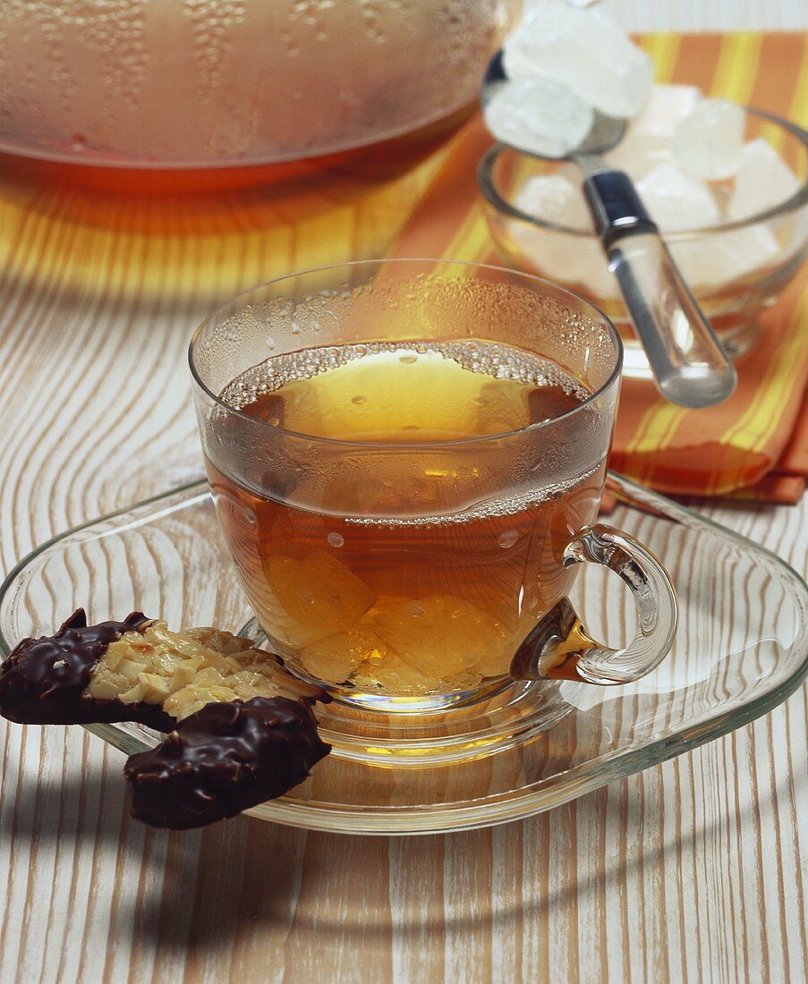 Black tea with sugar crystals and biscuit