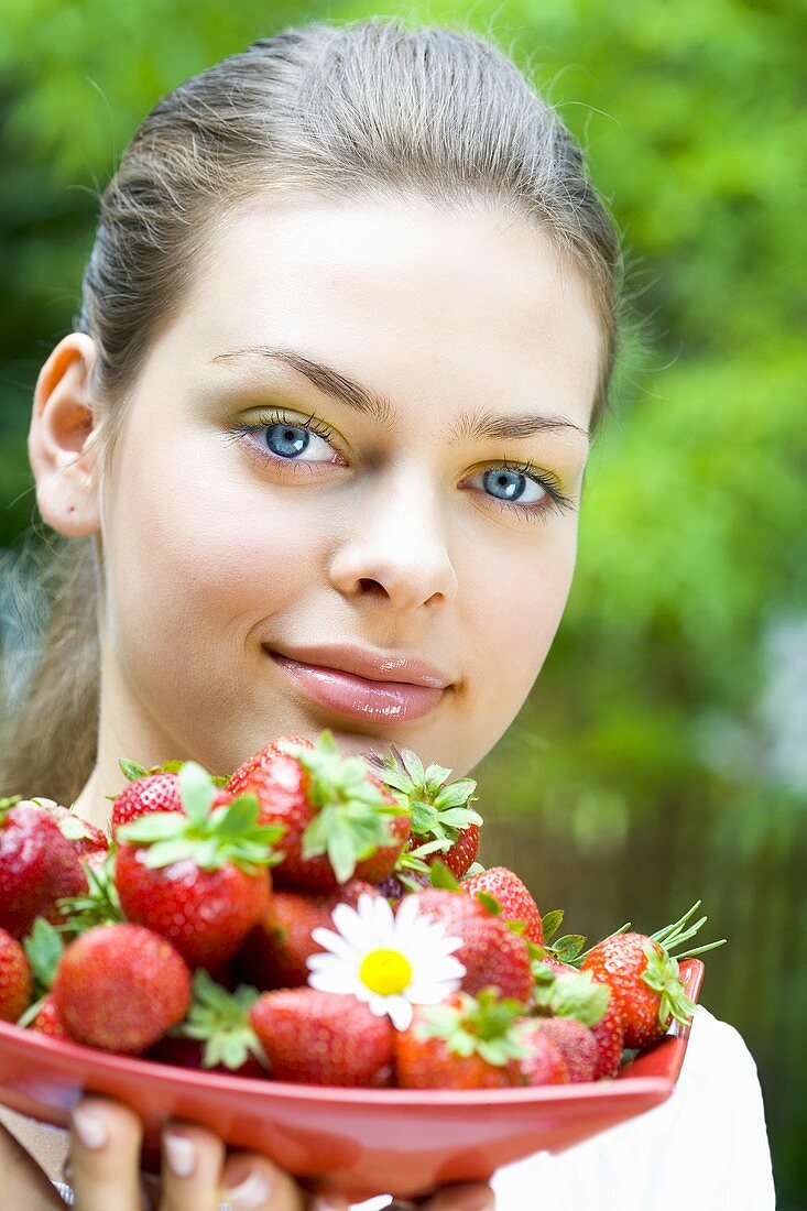 Junge Frau hält eine Schale Erdbeeren