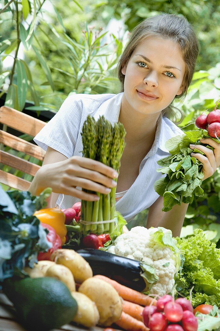 Junge Frau mit Spargel und Radieschen