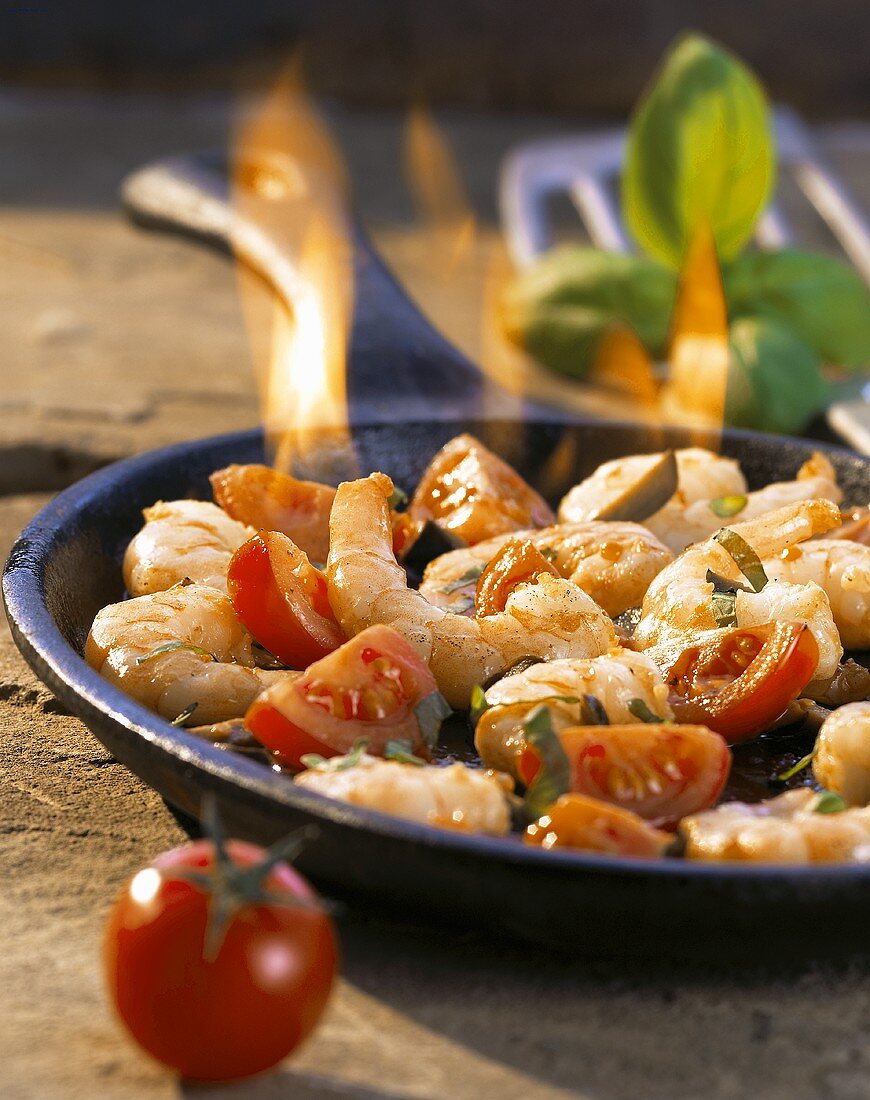 Flambéed shrimps with cocktail tomatoes and basil