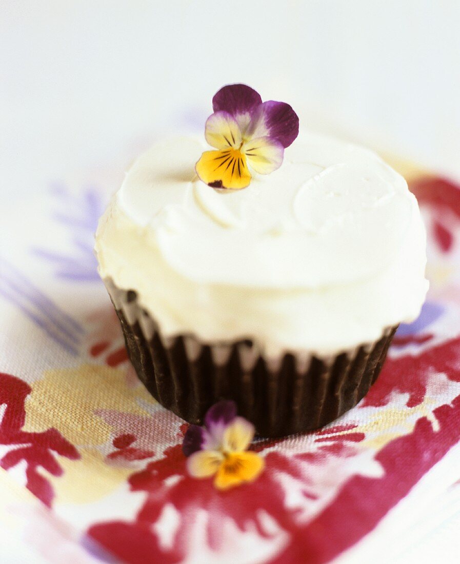 Chocolate muffin with icing and pansies