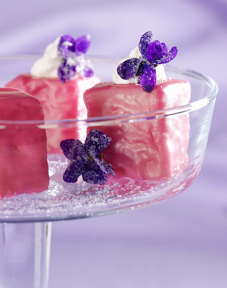 Petit fours mit rosa Zuckerguss und Veilchen