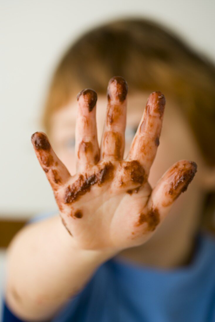 Kleiner Junge mit Schokoladen-Hand