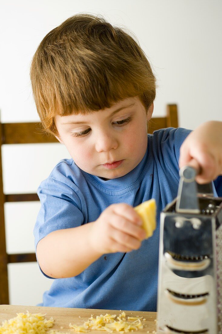 Kleiner Junge beim Käse reiben