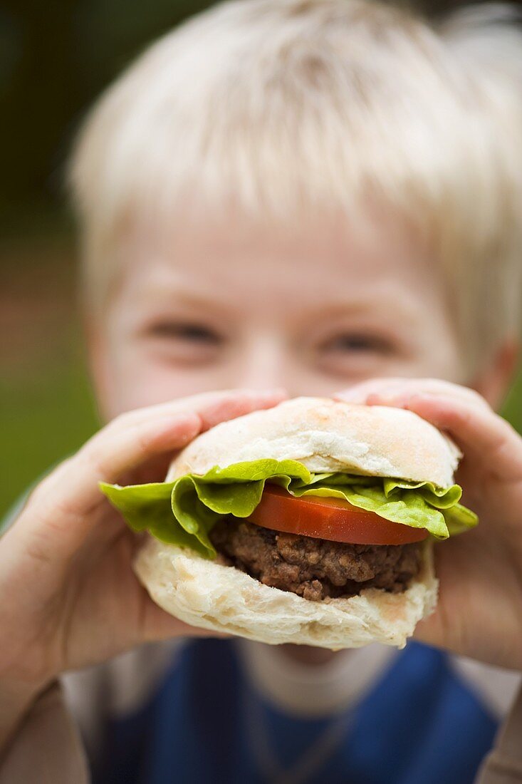 Small boy holding a burger