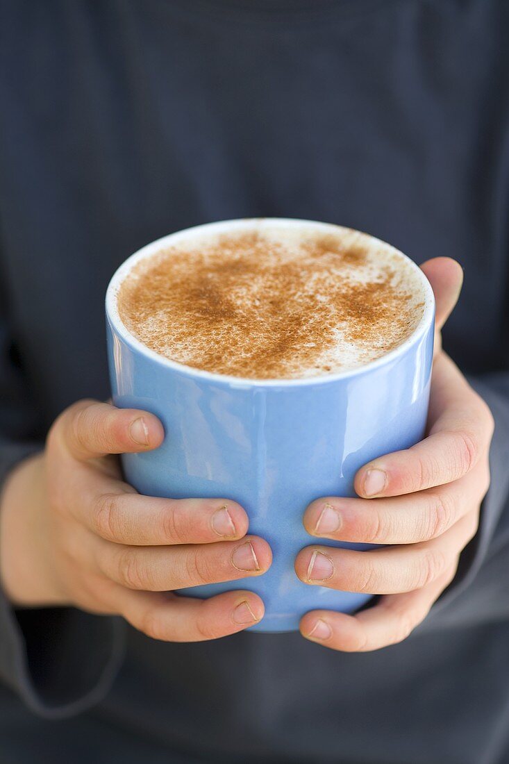 Child's hands holding a cup of hot chocolate