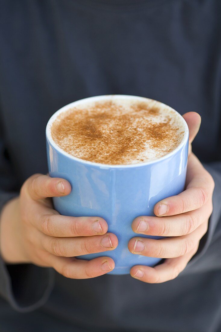 Kinderhände halten eine Tasse mit heißer Schokolade