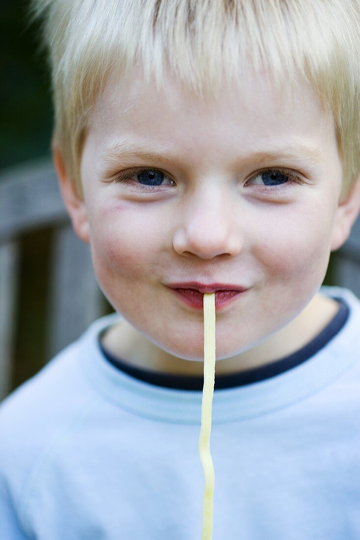 Small boy eating a piece of ribbon pasta