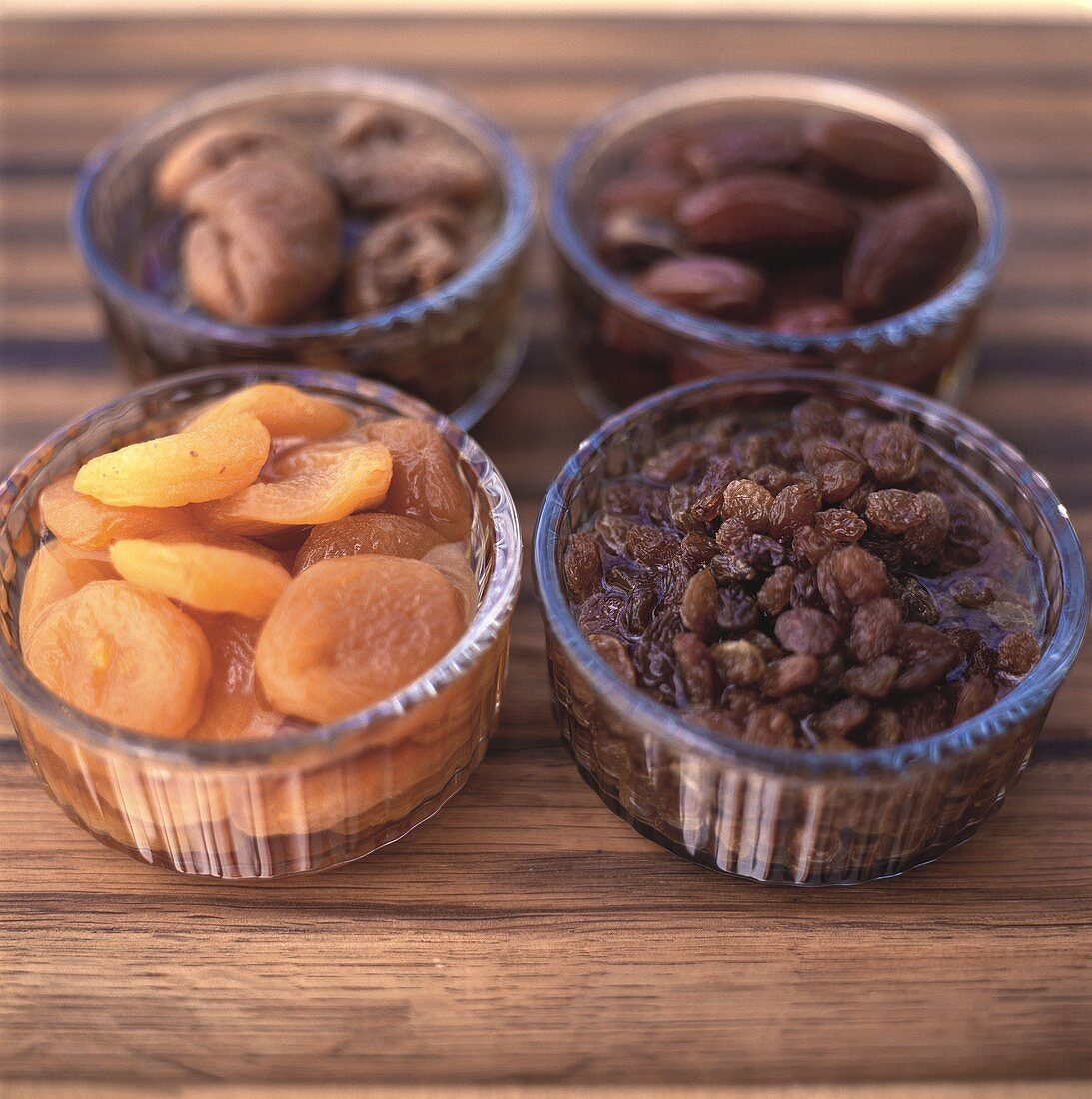 Four different dried fruits in small glass bowls