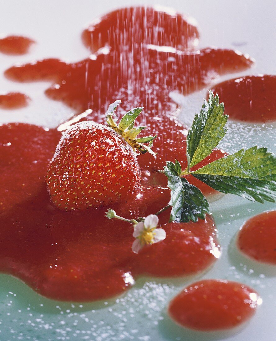 Strawberry with flower and leaf lying in strawberry sauce