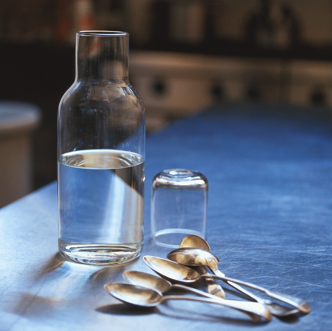 A bottle of water with glass and spoons