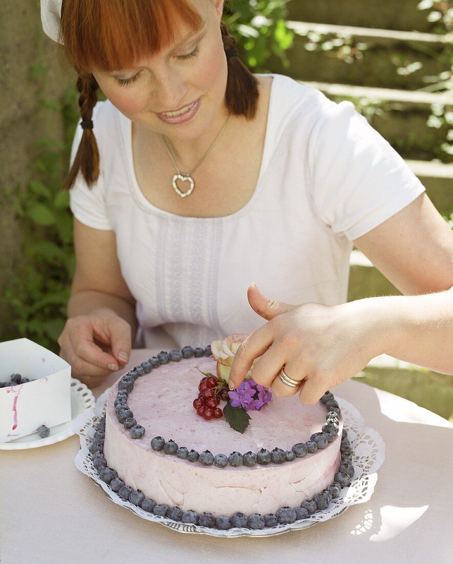 Woman decorating a blueberry cake
