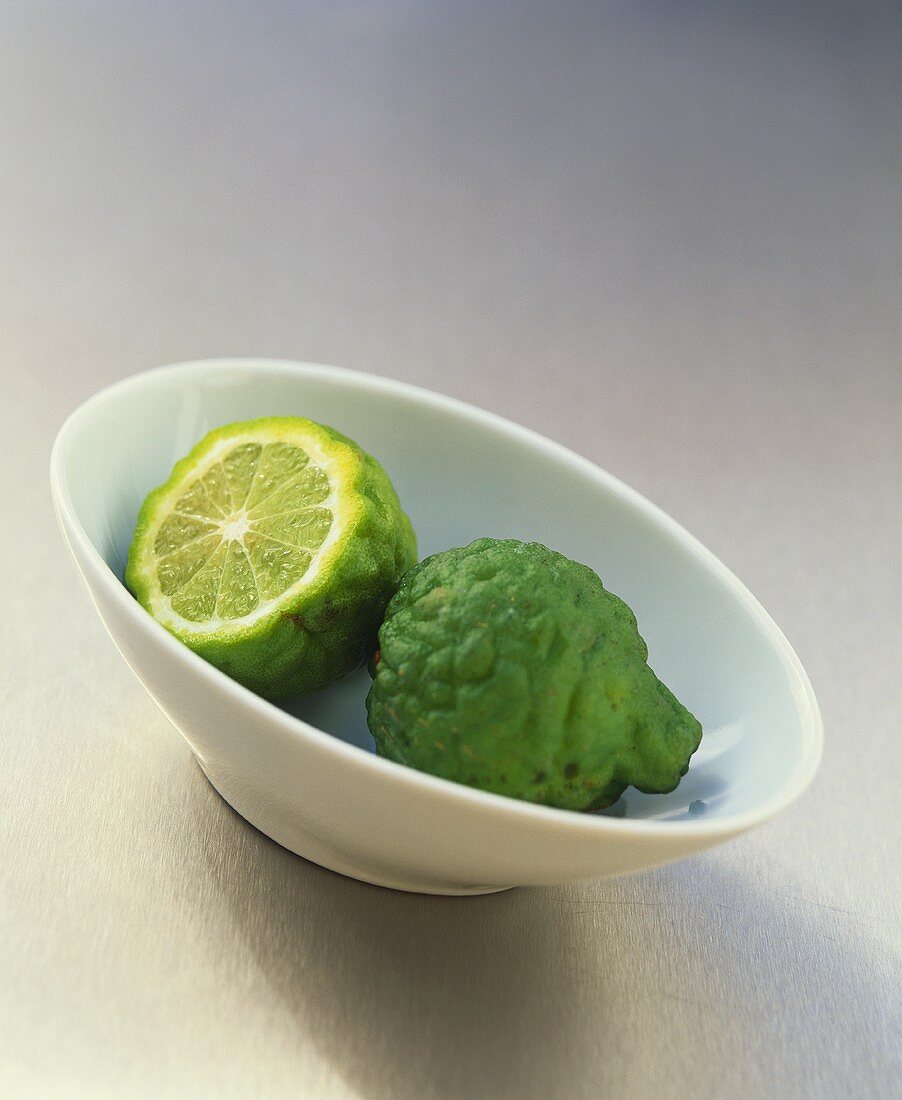 Two kaffir limes in a small bowl