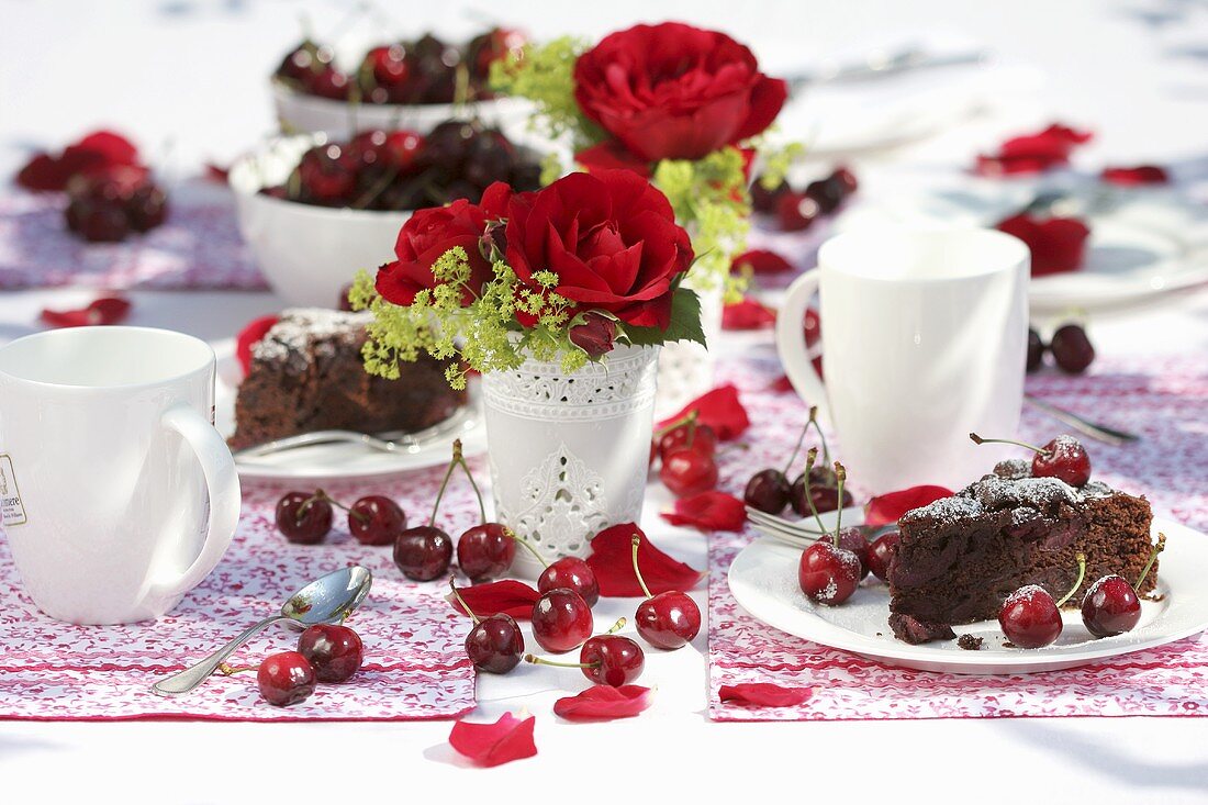 Two pieces of cherry cake on table with roses in vases