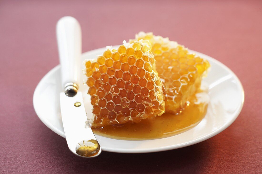 Two pieces of honeycomb with knife on a plate