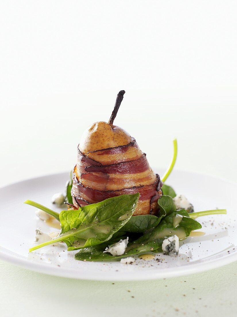 Pear wrapped in bacon on spinach salad