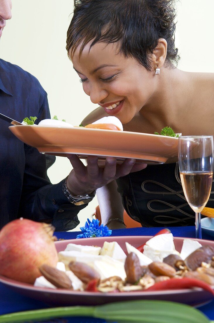 Woman smelling plate of tomatoes and mozzarella