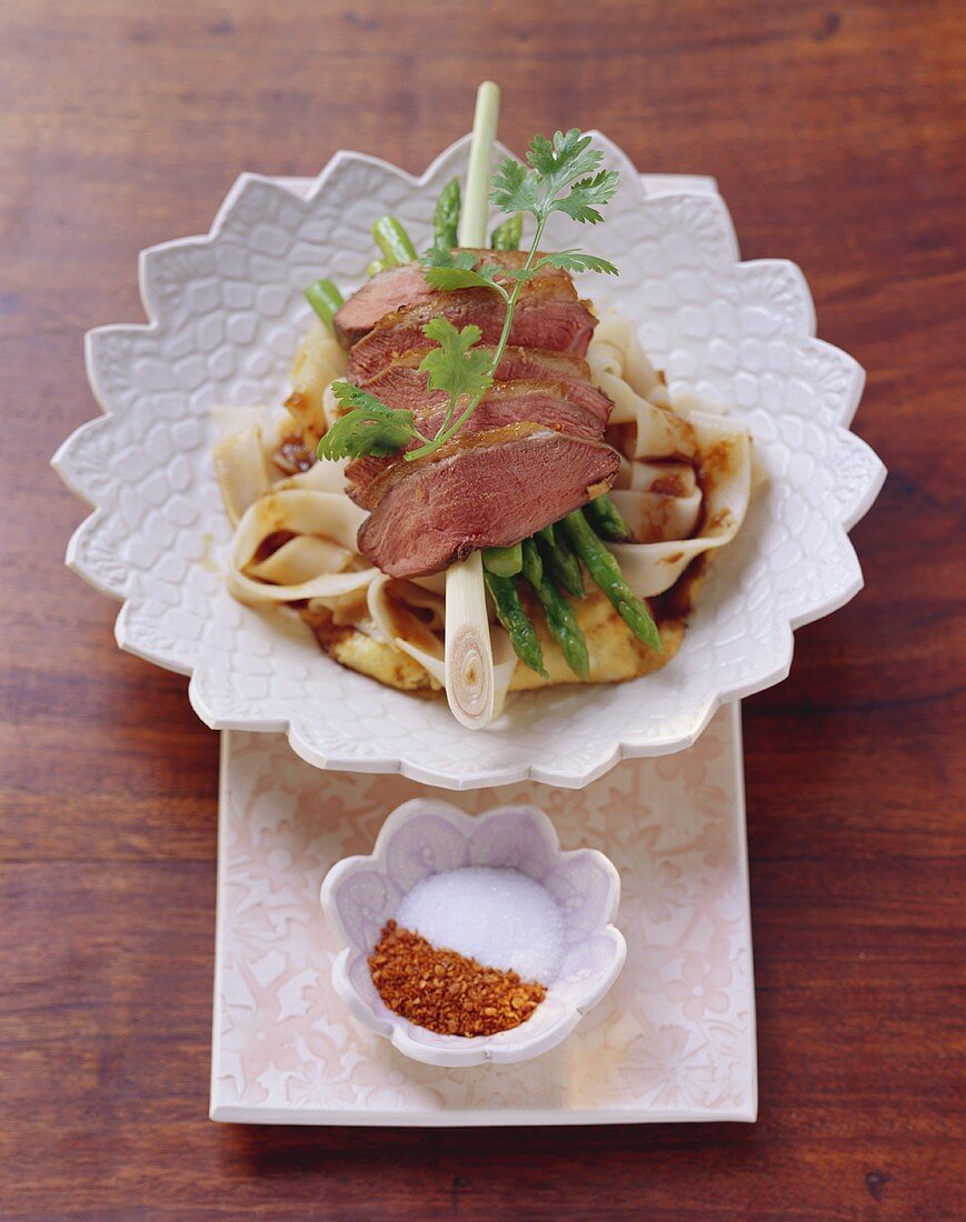 Roast duck breast on rice noodles with green asparagus