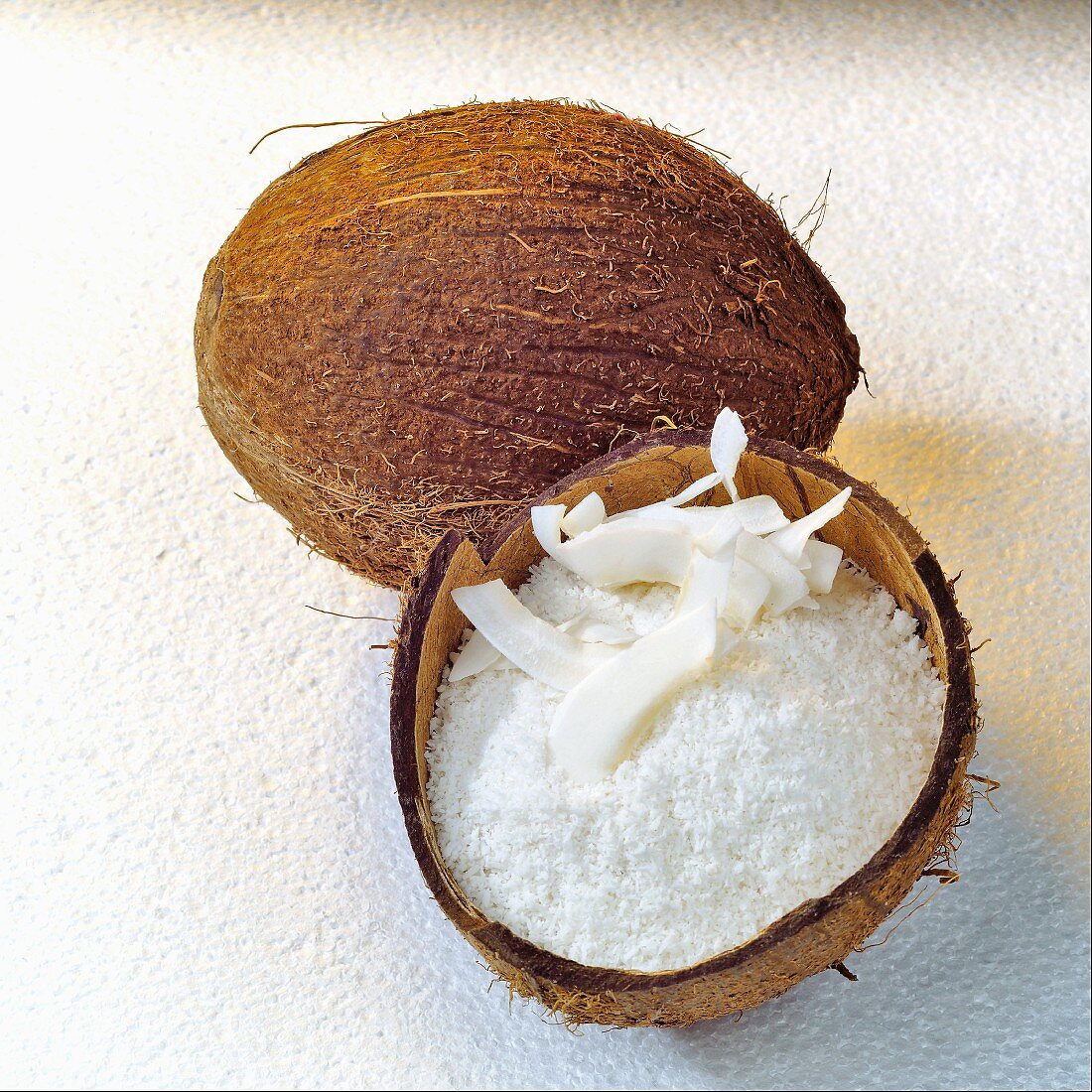 Grated coconut in coconut half and whole coconut
