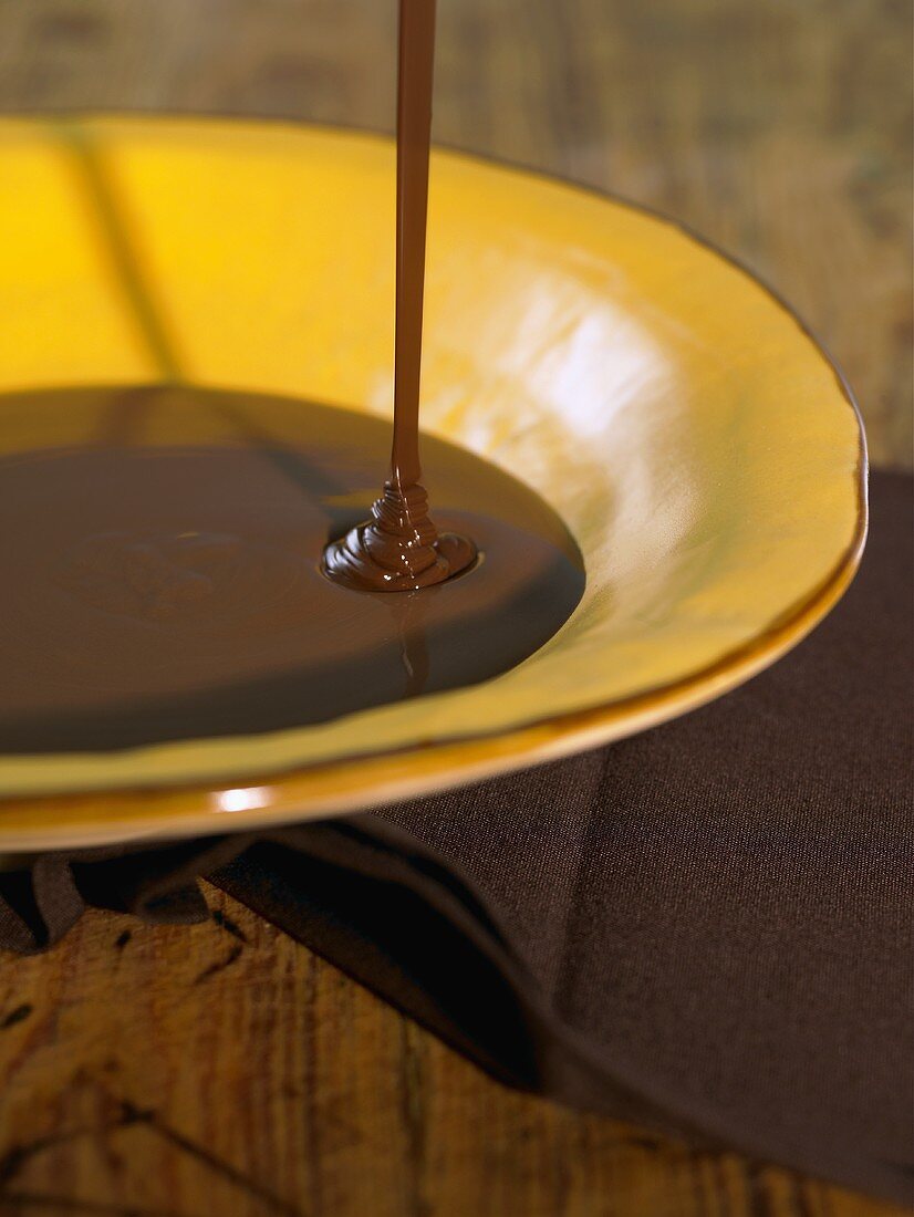 Geschmolzene Schokolade fließt in einen Teller