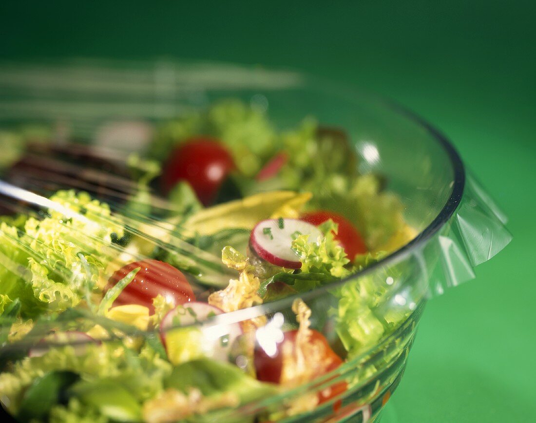 Mixed salad in a glass bowl covered with clingfilm