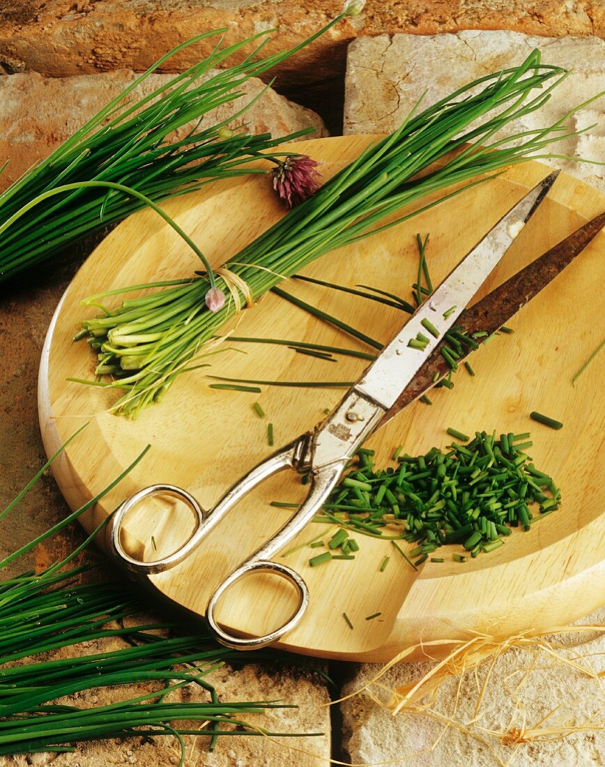 Chives and scissors on a wooden board
