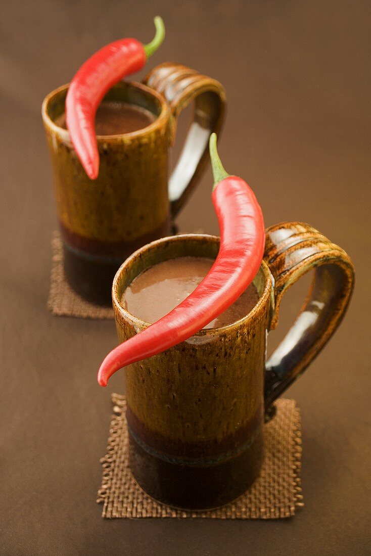 Two mugs of hot chocolate with chillies