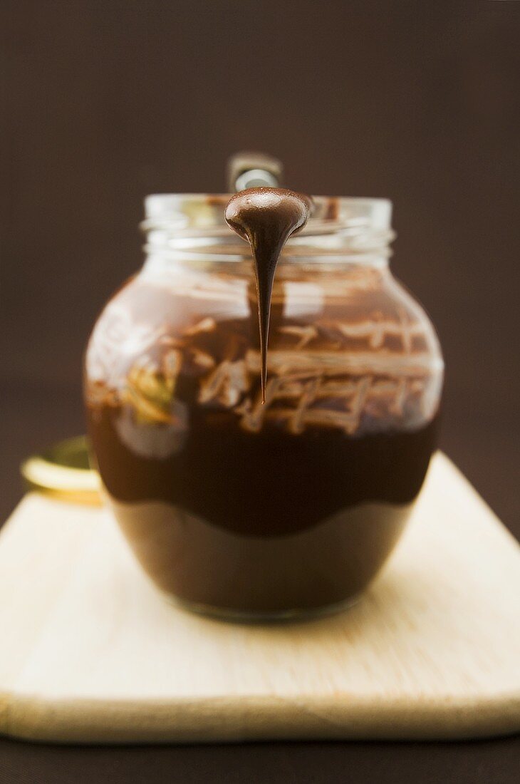 Chocolate spread in jar with knife on chopping board